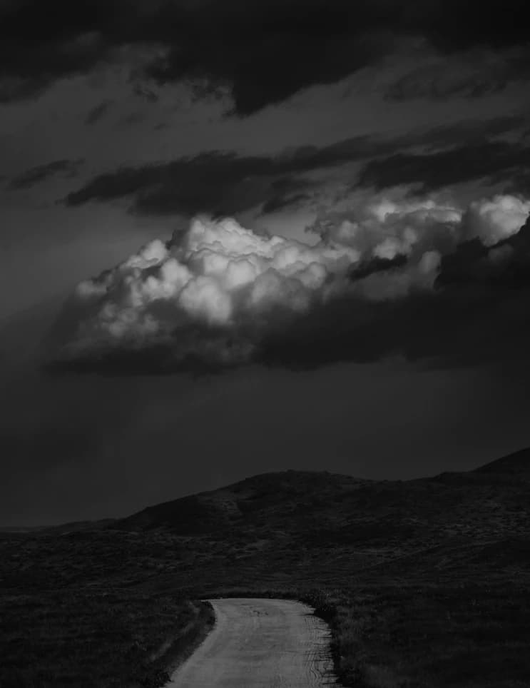 A picture of a road going off into the distance with clouds above.